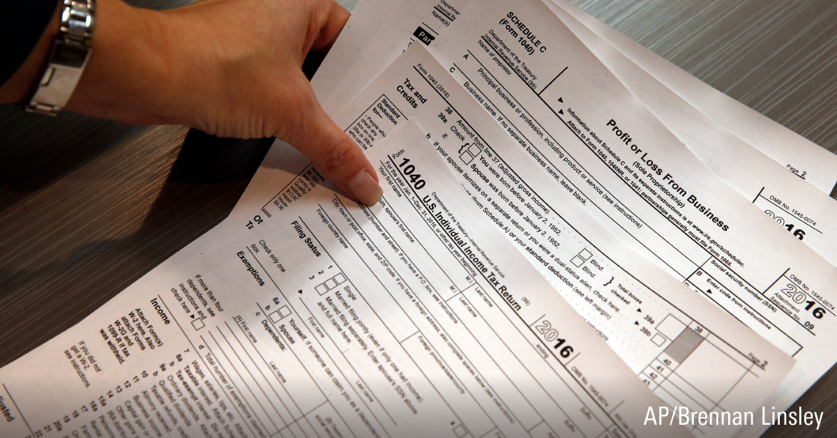 Person placing a few tax documents from the Internal Revenue of Service on a table